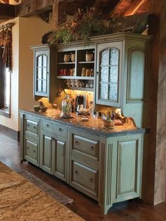 a kitchen with green cabinets and marble counter tops