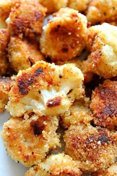 some fried food on a white plate with parmesan cheese and seasoning sprinkles