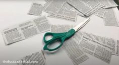 a pair of green scissors sitting on top of a pile of paper with cut out words