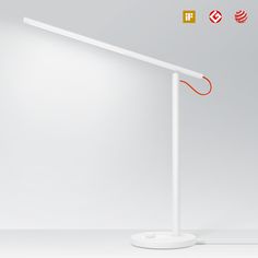 a white desk lamp sitting on top of a table next to an orange light bulb