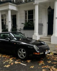 a black porsche parked in front of a white house