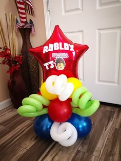 balloon bouquet in the shape of a star with balloons attached to it, sitting on a wooden floor next to a door