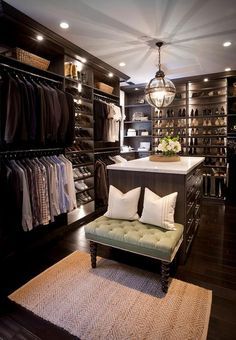 a walk - in closet with lots of clothes on shelves and a bench next to it