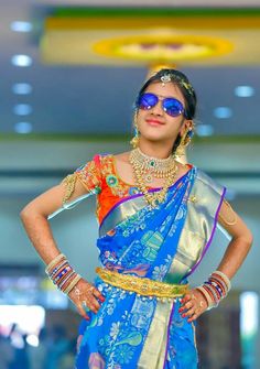 a woman in a blue and gold sari is standing with her hands on her hips