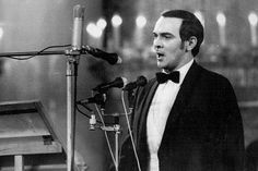 a man in a tuxedo standing next to a microphone