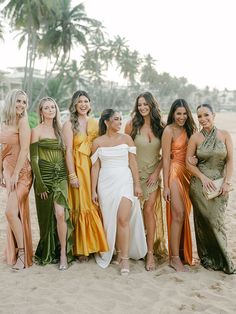 a group of women standing next to each other on top of a sandy beach