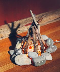 a fire pit made out of rocks and wood on the floor next to a red wall