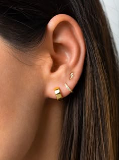 a woman's ear is shown with two small gold bars in the middle of it