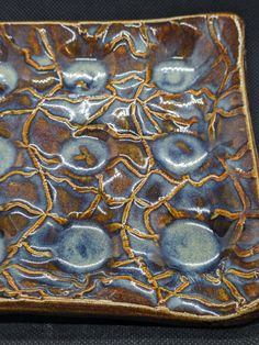 a brown and blue ceramic dish on a black surface