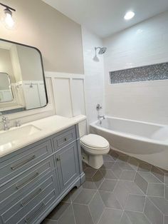 a bathroom with a toilet, sink and bathtub next to a mirror on the wall