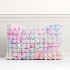 a multicolored pillow sitting on top of a white floor next to a wall