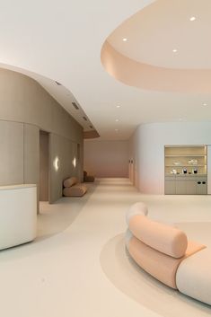 an empty room with white furniture and circular lights on the ceiling is lit by recessed lighting