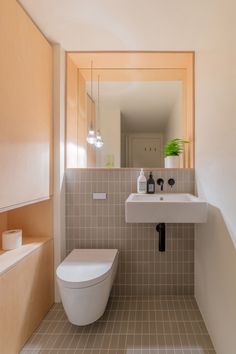 a white toilet sitting next to a bathroom sink under a mirror in a room with beige walls