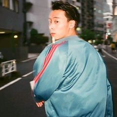 a man in a blue jacket is standing on the street