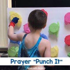 a young boy is playing with magnets on a bulletin board that says prayer punch it