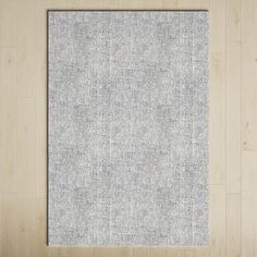 a white and gray rug sitting on top of a wooden floor