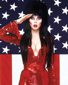 a woman with long black hair in front of an american flag wearing a red sequin dress