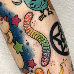 an arm with colorful tattoos on it and stars, moon, and other things in the background