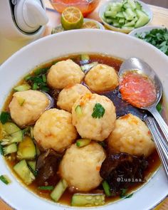 a white bowl filled with meat and vegetables next to other foods on a table top