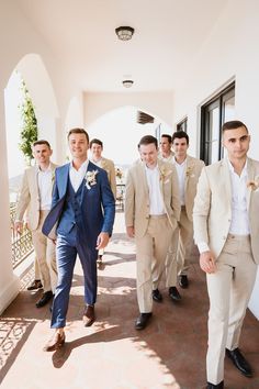 a group of men in suits walking down a hallway