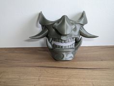 a mask that is sitting on top of a wooden table next to a white wall