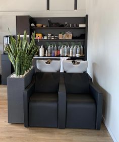 two black couches sitting next to each other in front of a shelf with bottles on it