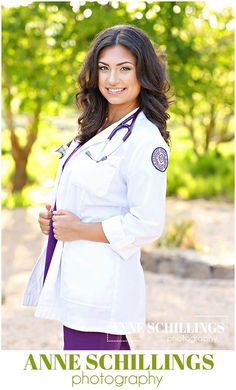 a woman in white coat and purple pants posing for a photo with trees in the background