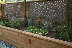 a wooden planter filled with lots of flowers next to a fenced in area