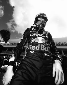 a black and white photo of a man sitting on the side of a race track