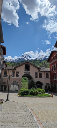 a building with mountains in the background and blue sky above it, on a cobblestone street