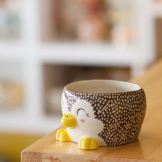 a ceramic penguin cup sitting on top of a wooden table