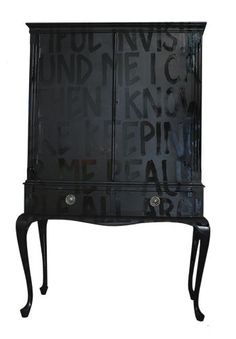 a black cabinet with writing on the front and bottom, sitting against a white background