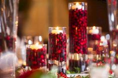 a table topped with lots of candles covered in pomegranates and greenery