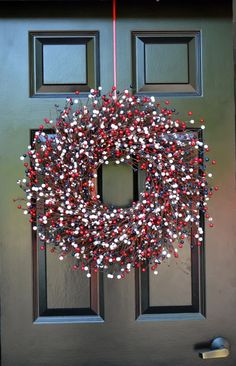 a wreath hanging on the front door of a house with red, white and blue decorations