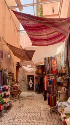 an outdoor market with lots of cloths hanging from the ceiling