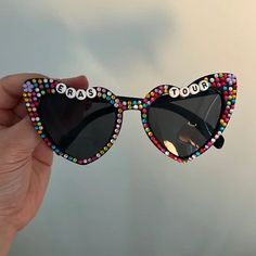 a person holding up a pair of sunglasses with the word tour written on them