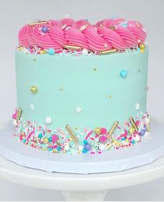 a blue cake with pink frosting and sprinkles sitting on top of a white plate