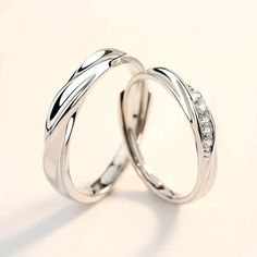 two white gold wedding rings with diamonds on each one, set against a plain background