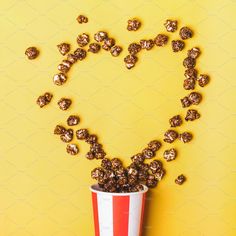 a red and white striped bucket filled with chocolate candies on top of a yellow background