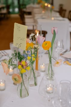 flowers in vases are on the table at a wedding reception with candles and cards