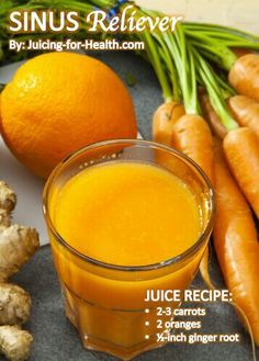 an orange juice in a glass next to carrots and ginger root