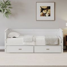 a white daybed with two drawers underneath it in a room next to a lamp