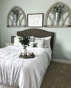 a bed with white sheets and pillows in a bedroom next to two framed pictures on the wall