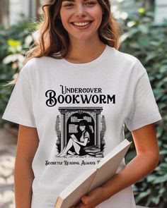 Celebrate your love for books discreetly with our Retro Vintage "Undercover Bookworm" shirt, the perfect attire for those who revel in their reading quietly or proudly. This retro-style tee is designed for romantasy readers, librarians, and all book lovers in between. It subtly nods to your bookish passions while maintaining a stylish and casual look that's suitable for any occasion--from book club meetings to everyday wear. Made from soft, comfortable fabric, it's ideal for long reading session Bookworm Shirt, Book Club Meeting, Wardrobe Upgrade, Gifts For Librarians, Retro Mode, Fashion Things, Retro Stil, Librarian, Shirt Price