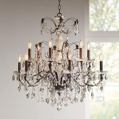 a chandelier hanging from the ceiling in a room with white walls and windows