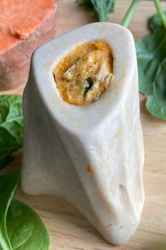 an egg roll is cut in half on a cutting board next to some leaves and other vegetables