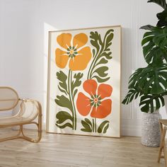 an orange and green flower print on a white wall next to a wicker chair