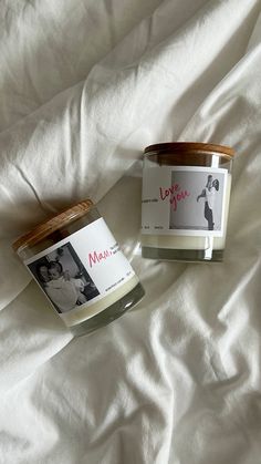 two candles sitting on top of a bed next to each other with the label love you