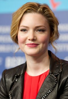 a close up of a person wearing a black leather jacket and red shirt with a blue background