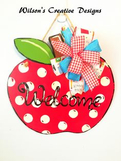 a red apple with a bow hanging from it's side on a white wall